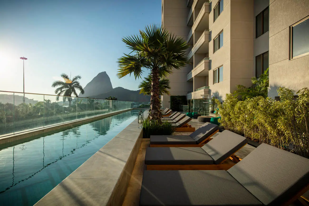 Piscina e espreguiçadeiras no terraço do Rio By Yoo, com paisagem do Rio ao fundo.